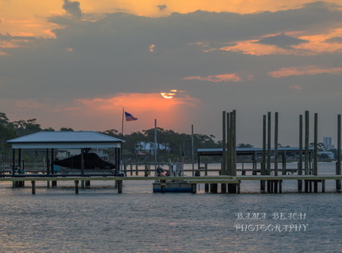 Warm sunset settling behind docks and covered boat slips at an Alabama Gulf Coast marina.